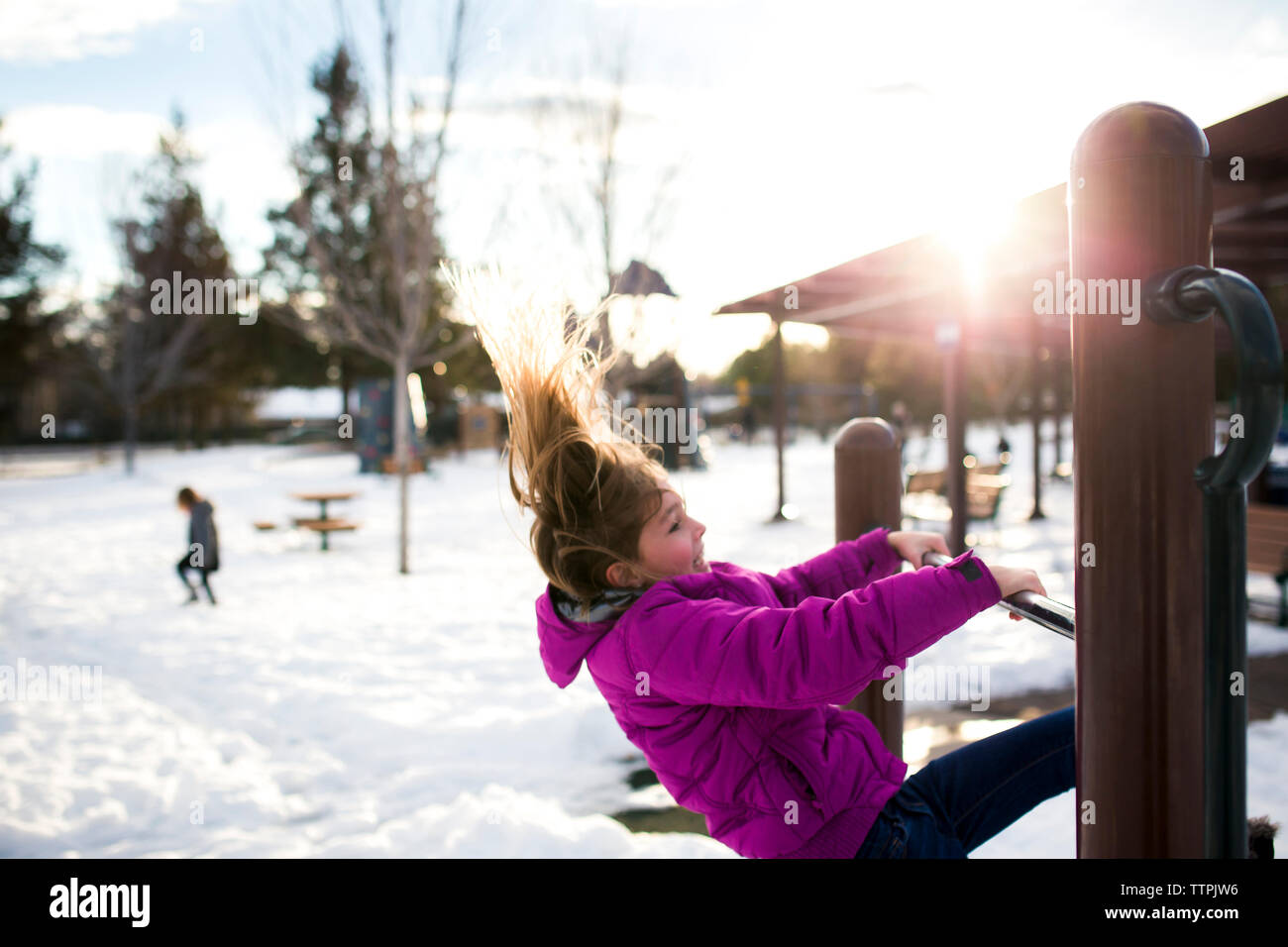 Girl playing on wooden structure at park during winter Stock Photo