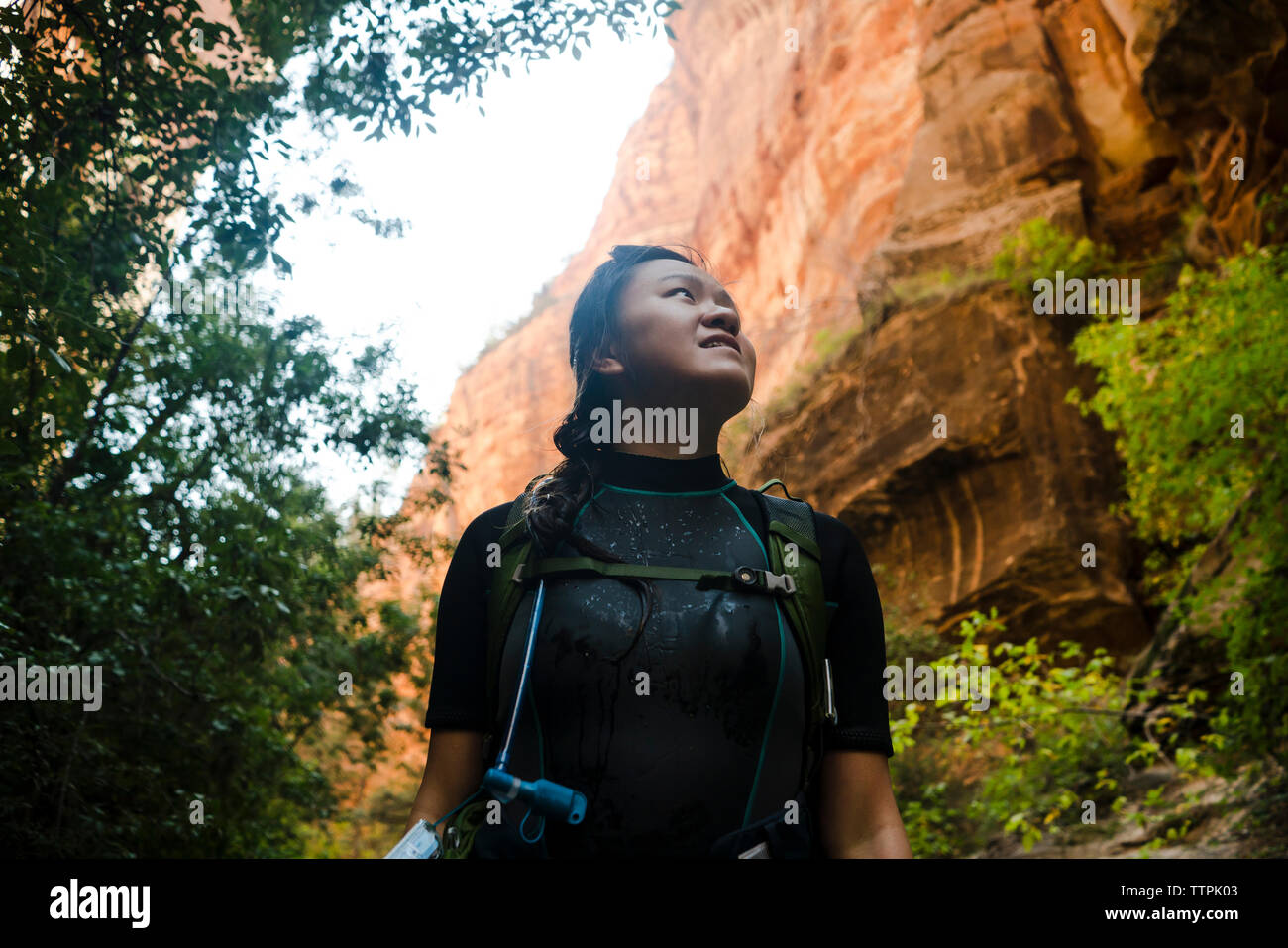 Low angle view of happy woman looking away while standing by rock formation Stock Photo