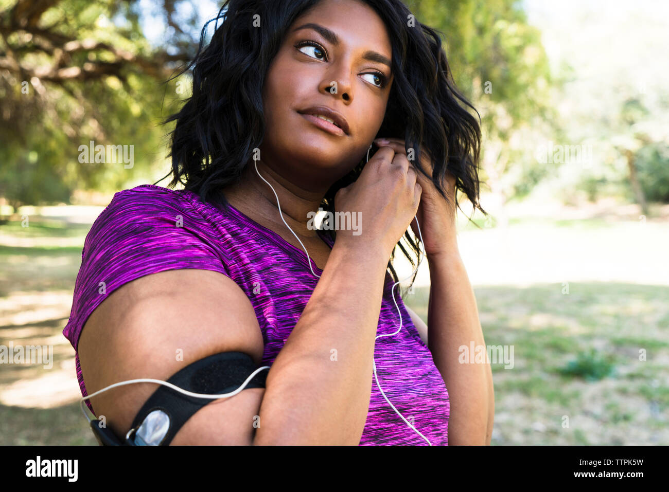Woman wearing earphones while exercising at park Stock Photo