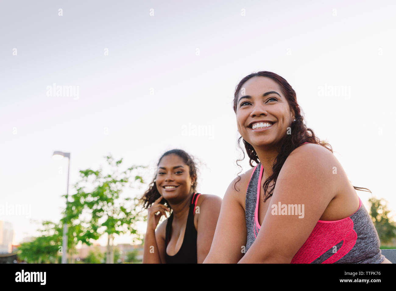 Happy sportswomen against clear sky at park Stock Photo