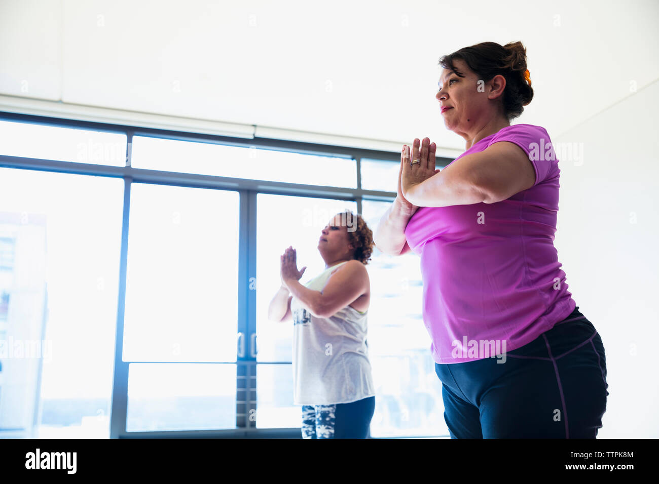 Low angle view of friends with hands clasped exercising in yoga studio Stock Photo