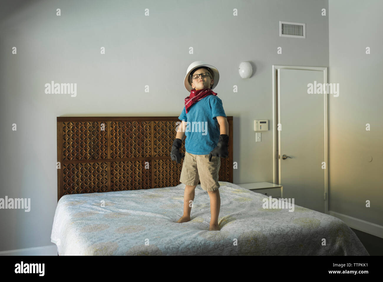 Boy wearing hat and gloves while standing on bed Stock Photo Alamy