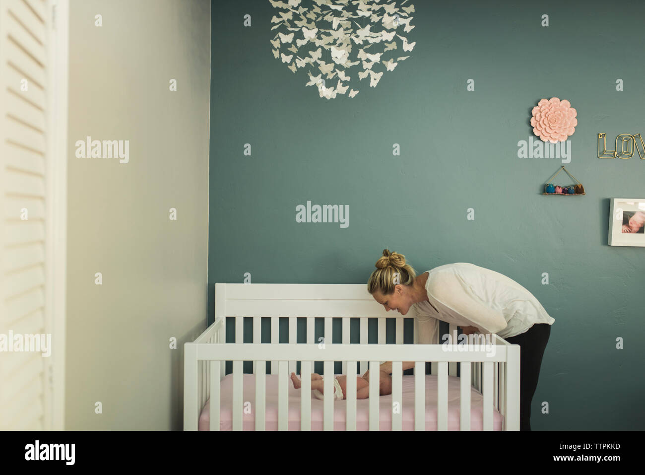 Mother looking at newborn daughter lying in crib against wall Stock Photo Alamy