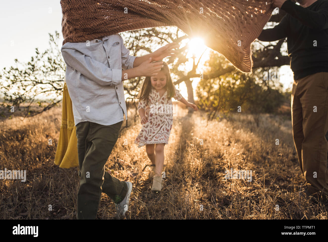 School age boy caught in blanket when running in California field Stock Photo