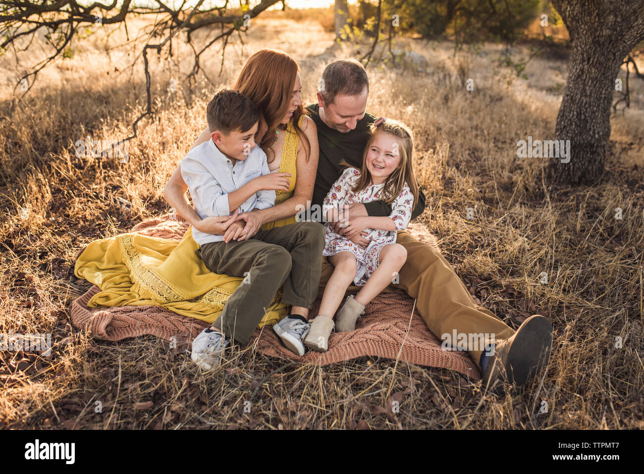Girl embraced by father and laughing while sitting in California field Stock Photo