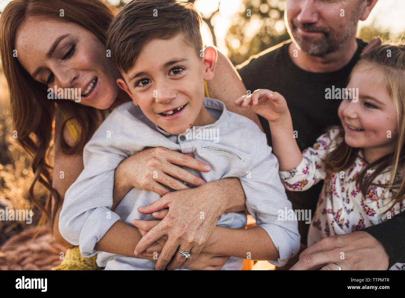 Close up of young boy laughing while being tickled by family Stock Photo