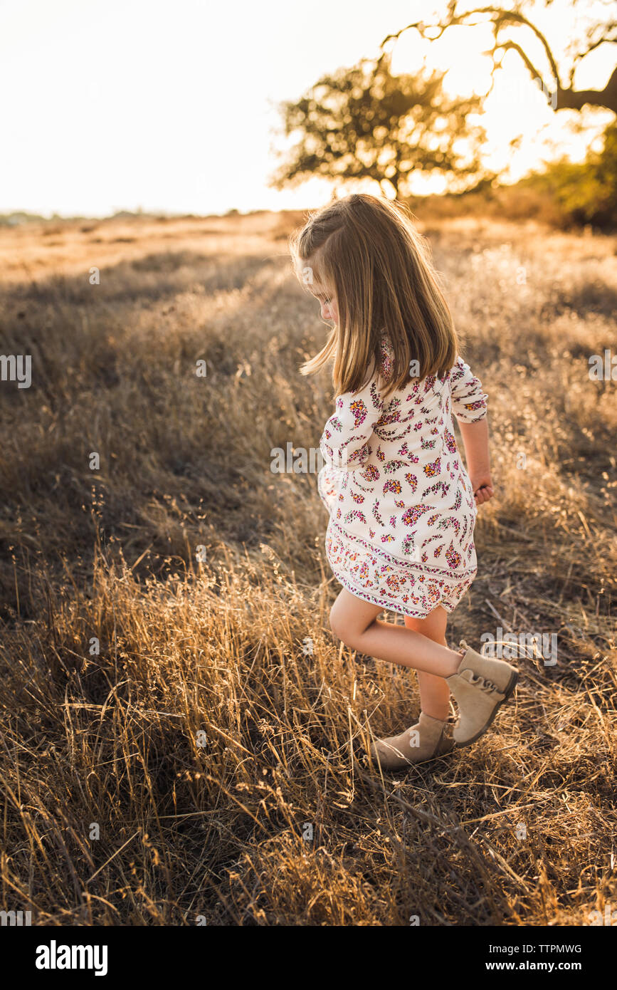 Young girl swinging dress in California field during sunset Stock Photo