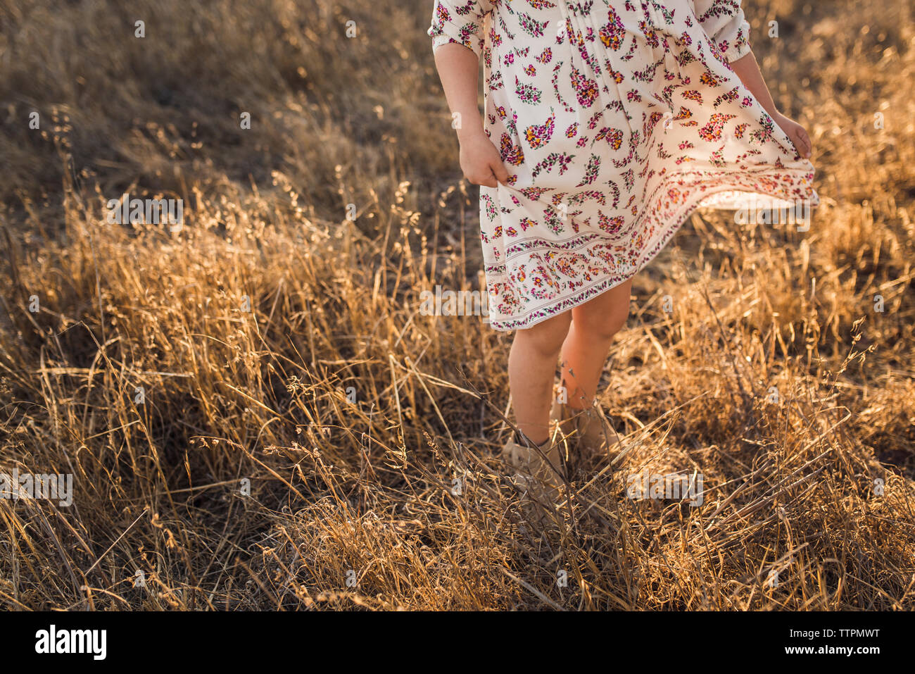 Young girl swinging dress in California field during sunset Stock Photo