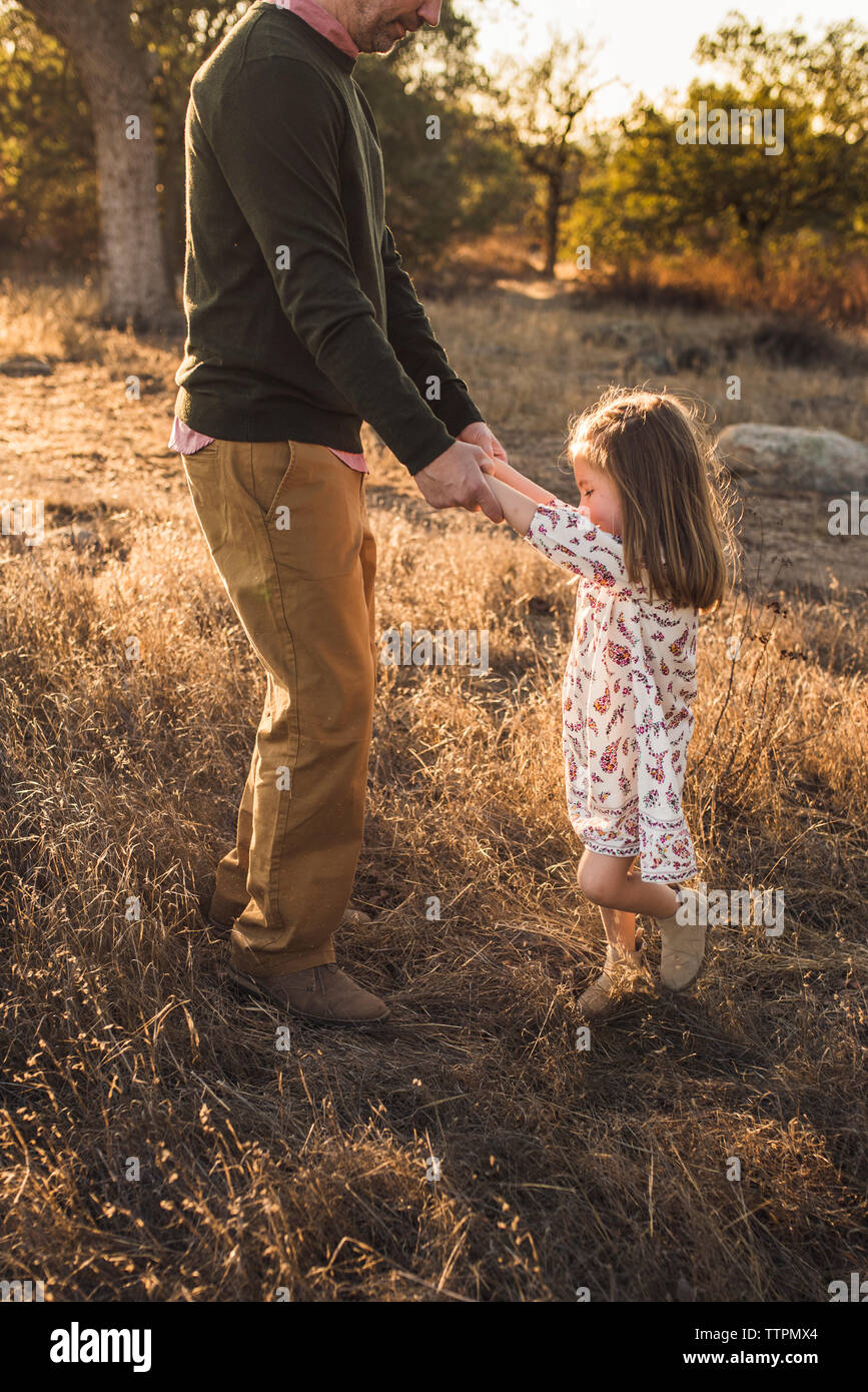 Father and daughter dancing in backlit California field during sunset Stock Photo