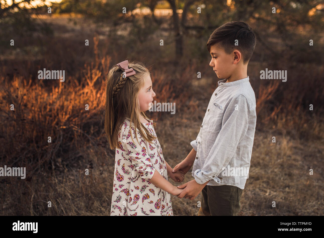 Young girl and boy looking at each other in California field at sunset Stock Photo