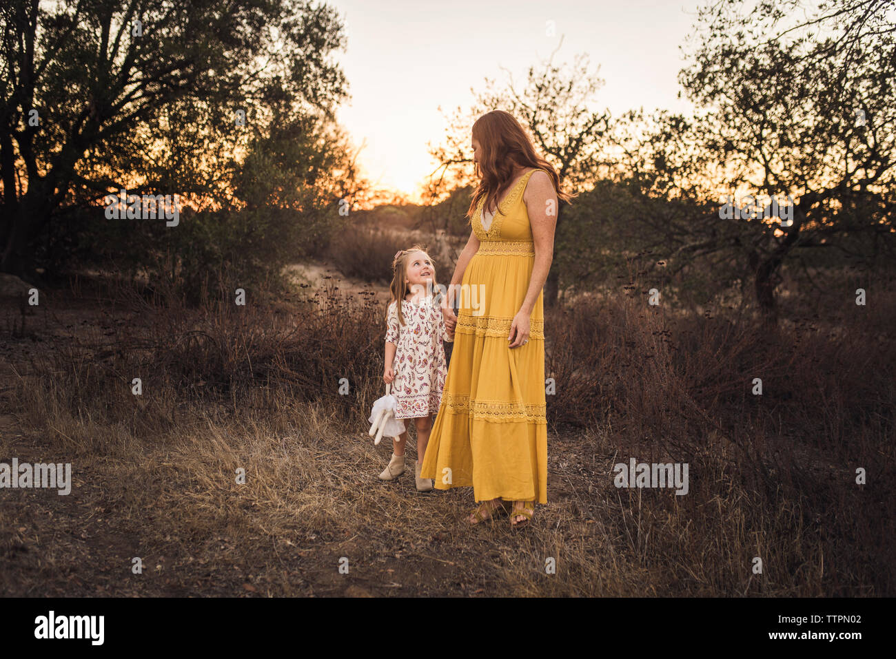 Young girl holding mothers hand while looking up in California field Stock Photo