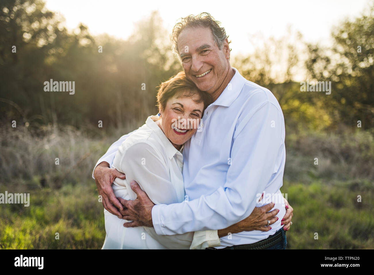 Senior couple hugging and smiling outside in backlight Stock Photo