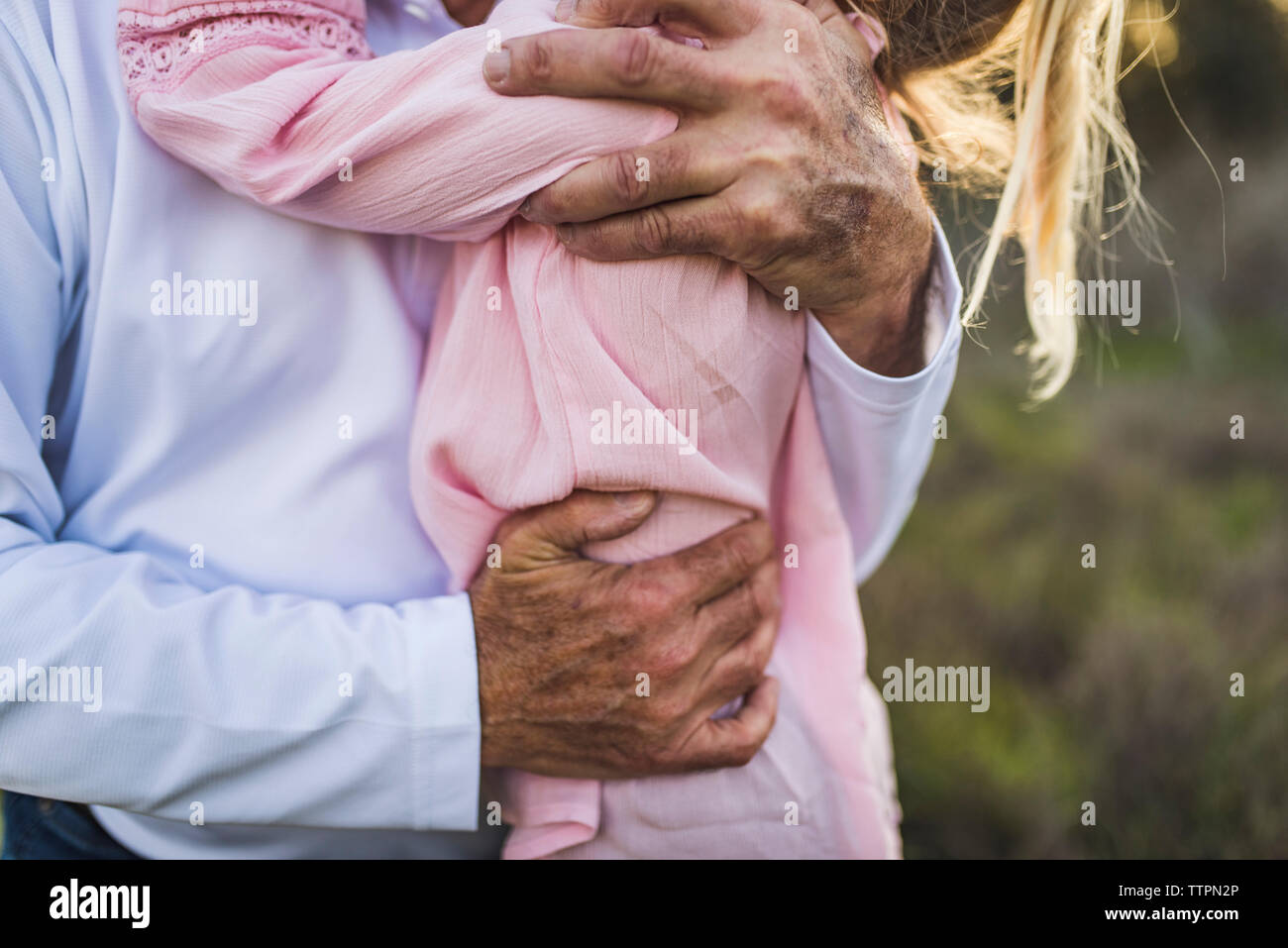 Close up of grandfathers arms wrapped around young granddaughter Stock Photo
