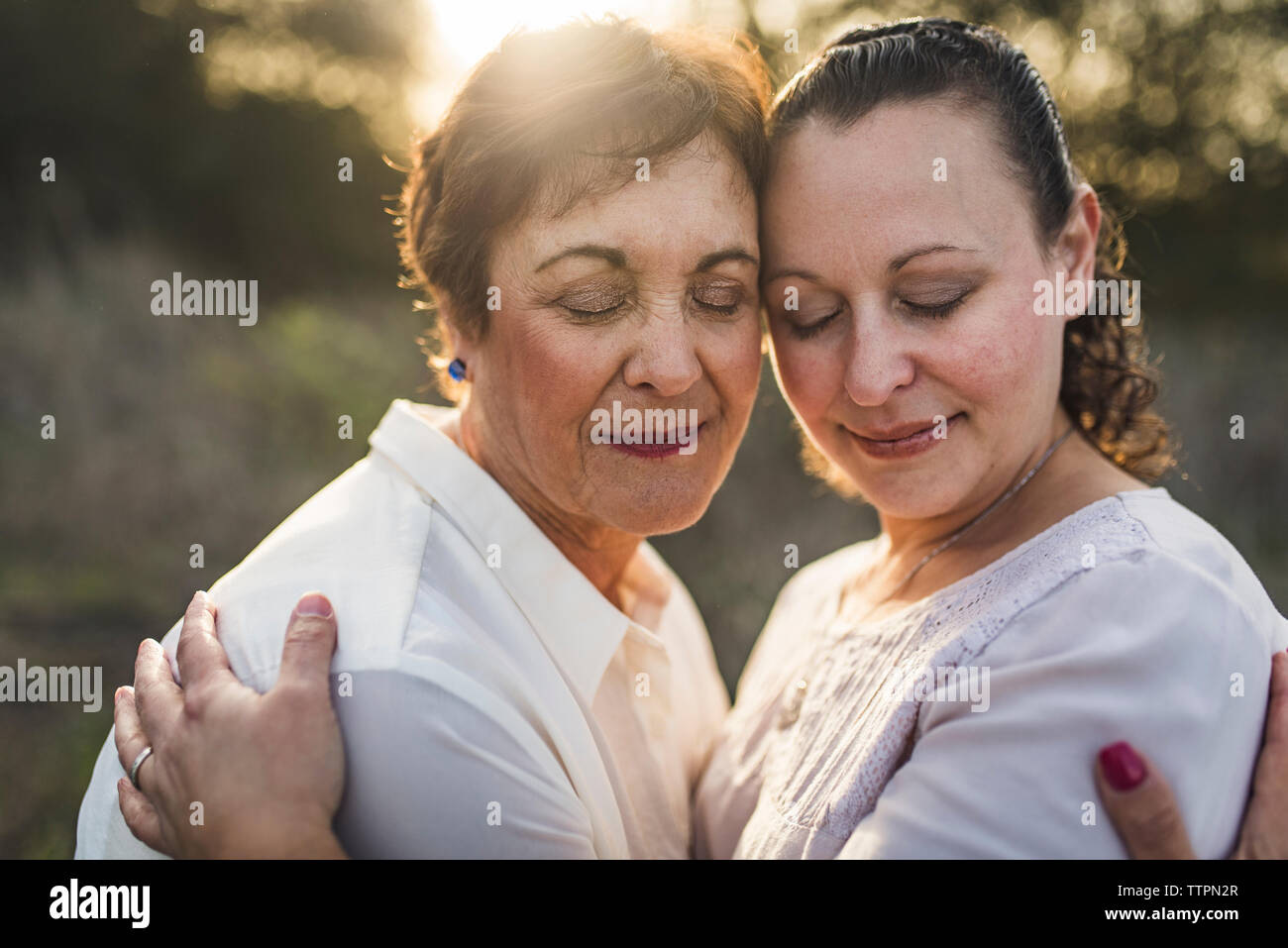 Close up of adult mother and daughter embracing and closing eyes Stock Photo