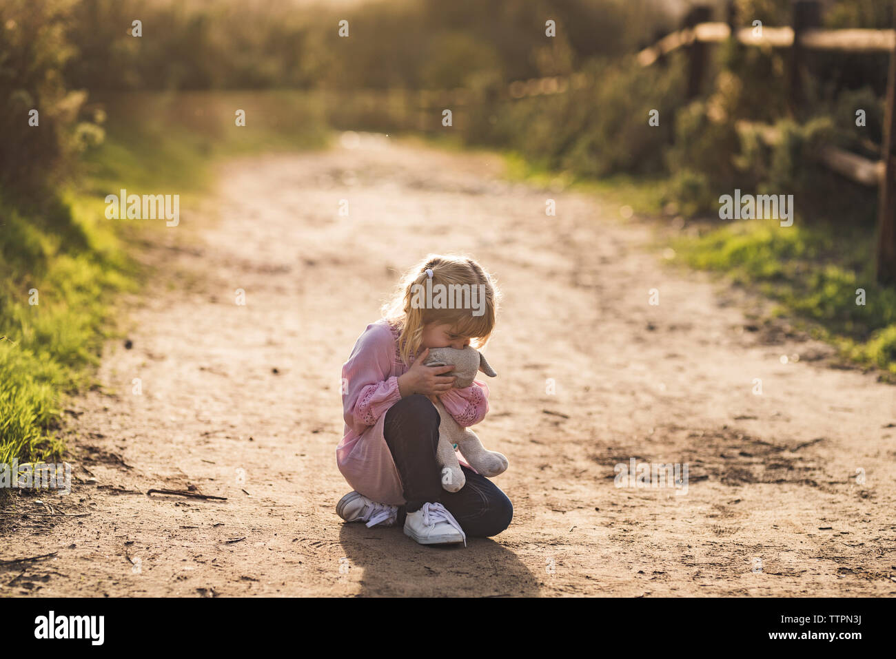 Little girl sitting on trail hugging her stuffed animal Stock Photo - Alamy