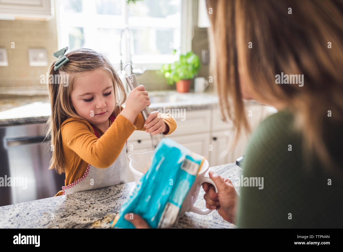Grandmother and granddaughter making breakfast pancakes in the kitchen Stock Photo