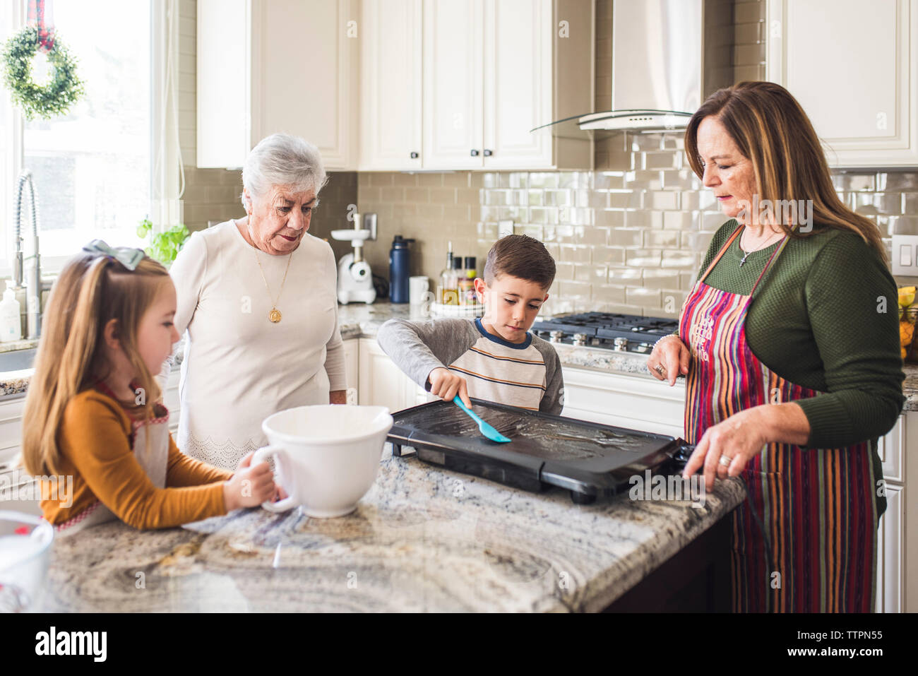 Grandparents and grandchildren cooking pancakes for breakfast Stock Photo