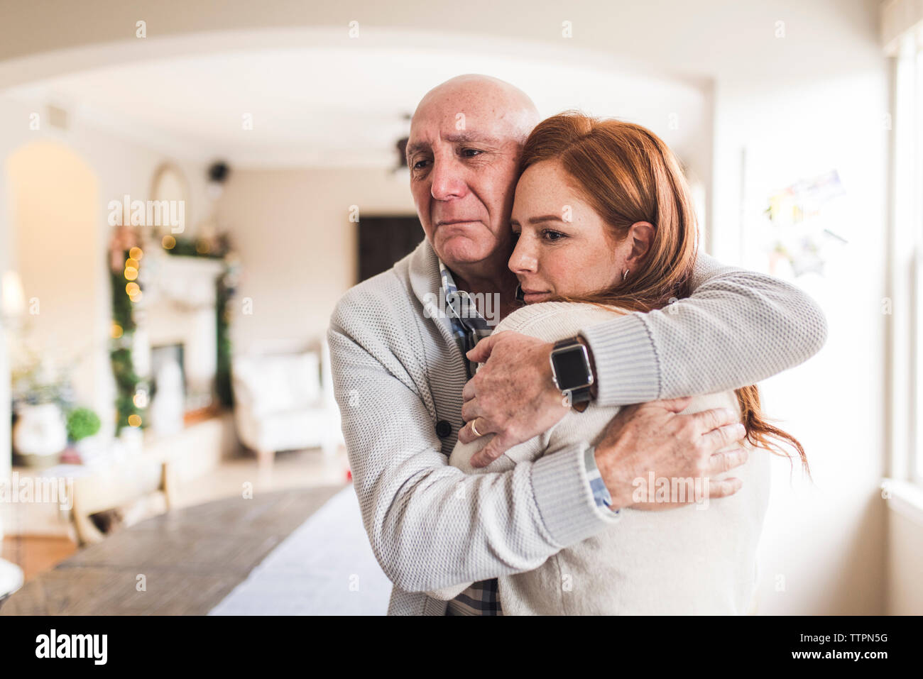 Portrait of father hugging adult daughter with tears in his eyes Stock Photo