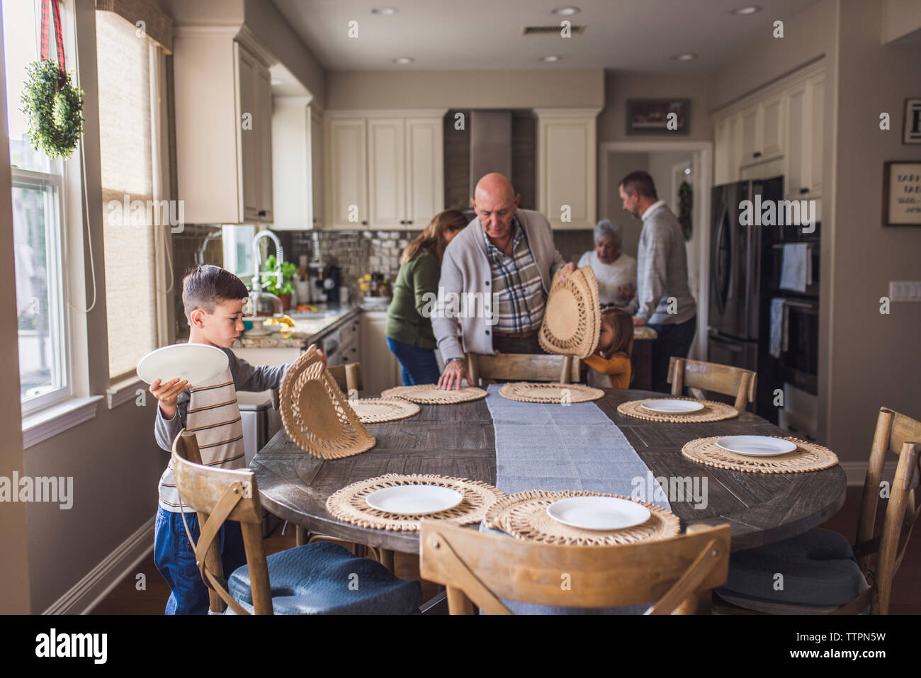 Family setting the kitchen table together for breakfast Stock Photo