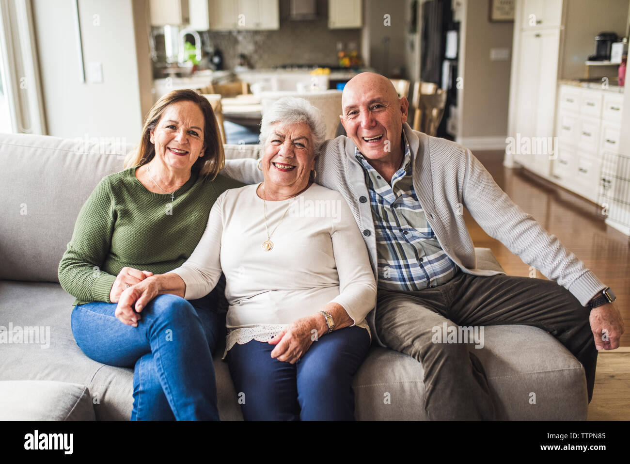 Portrait of multigenerational family sitting on living room couch Stock Photo