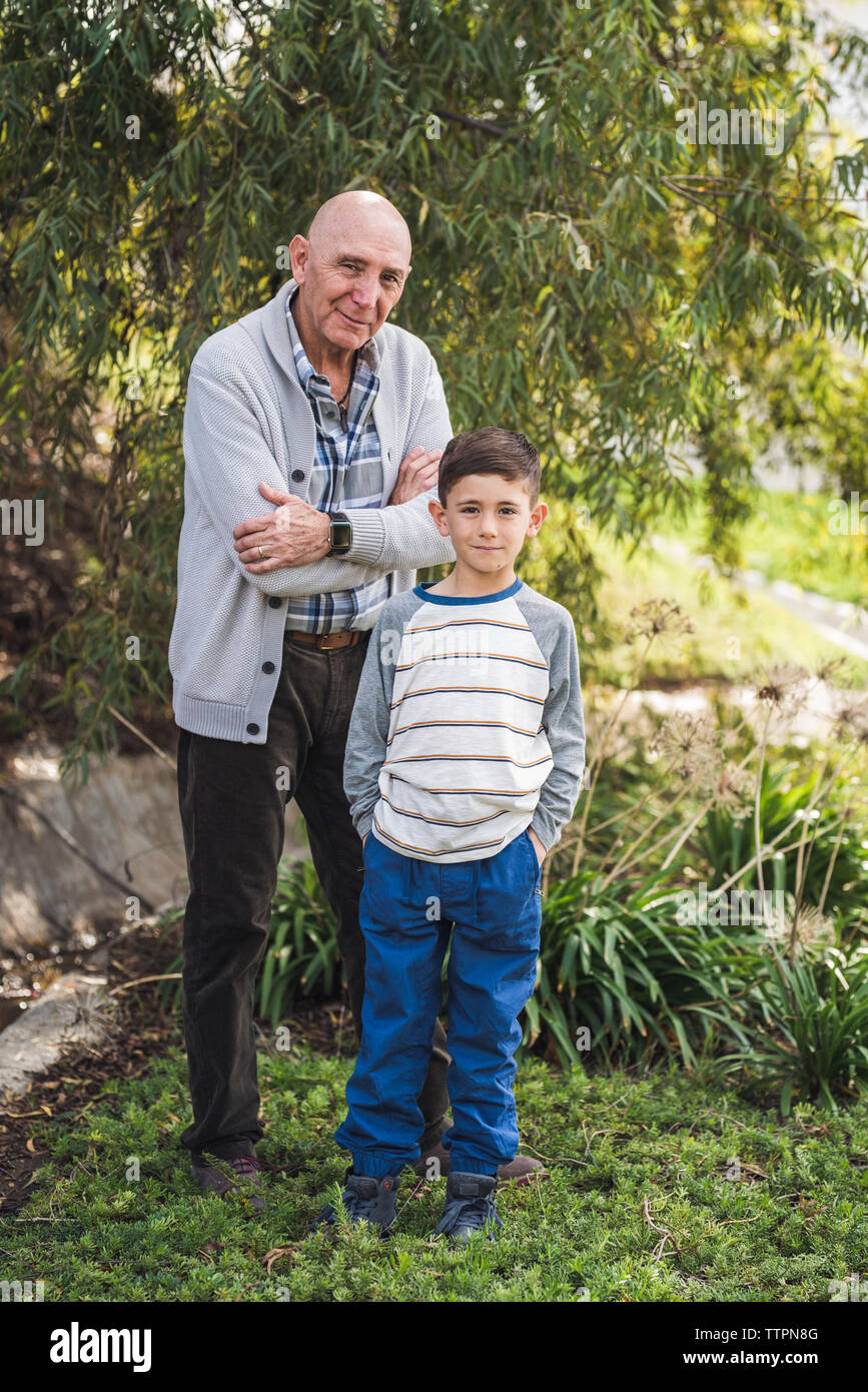 Portrait of grandfather and grandson standing outside in park Stock Photo