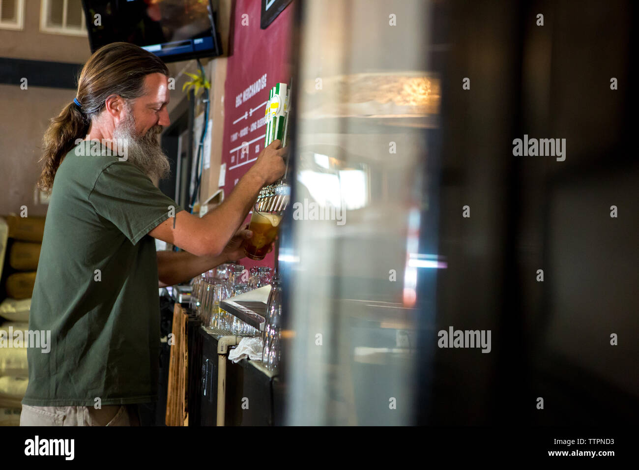 Side view of man pouring beer from tap Stock Photo