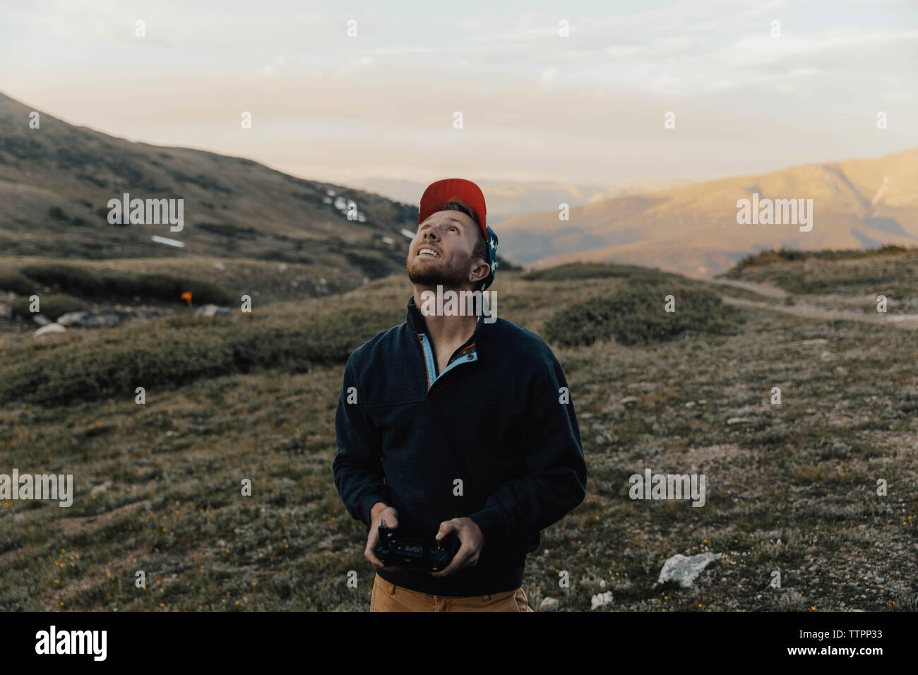 Man looking up while operating drone's remote control against mountains Stock Photo