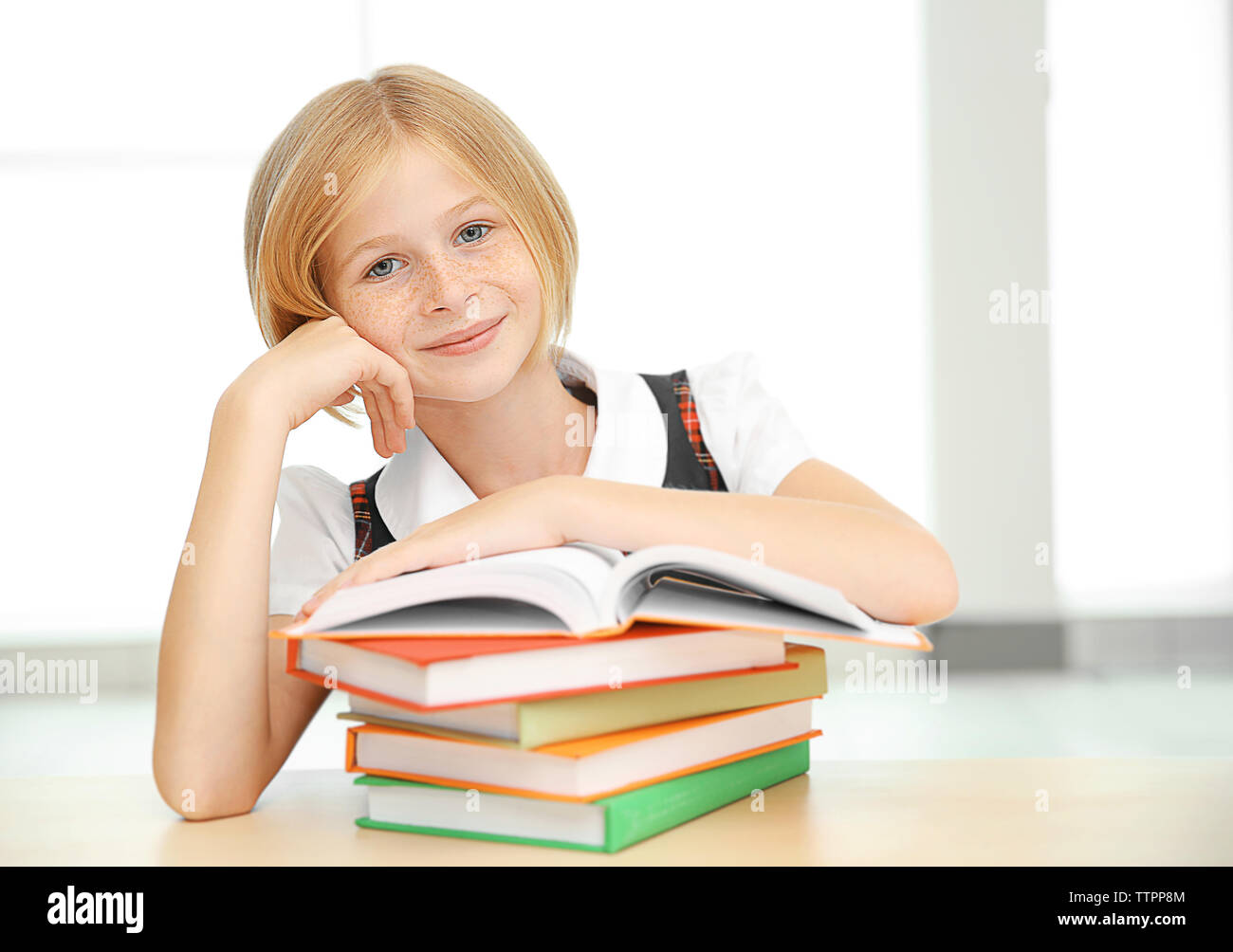 Smiling girl with many books at school Stock Photo - Alamy