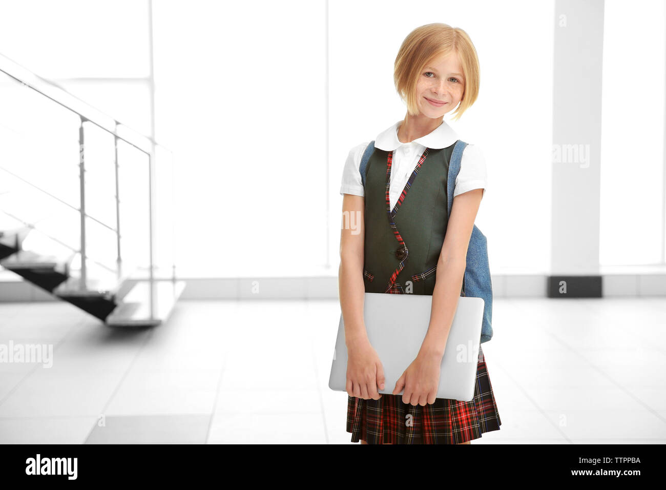 Cute schoolgirl with laptop on light background Stock Photo - Alamy