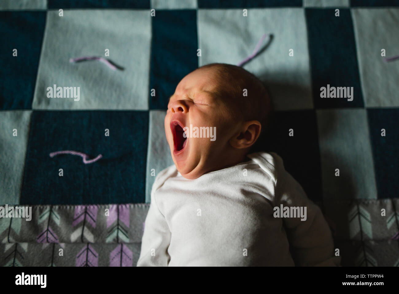 High angle view of cute baby girl yawning while sleeping on bed Stock Photo