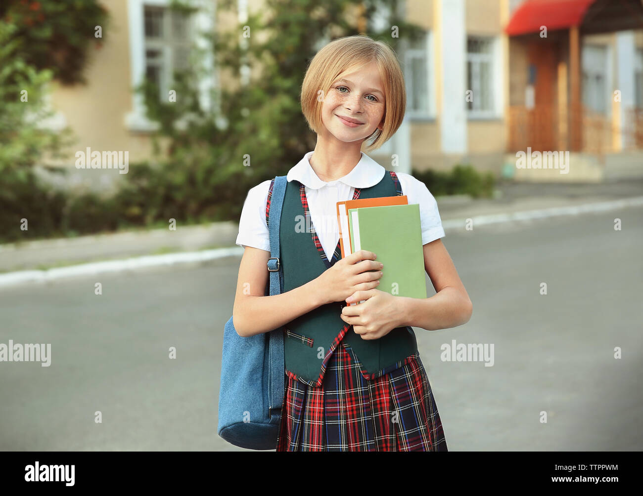 Cute schoolgirl with books on street Stock Photo - Alamy