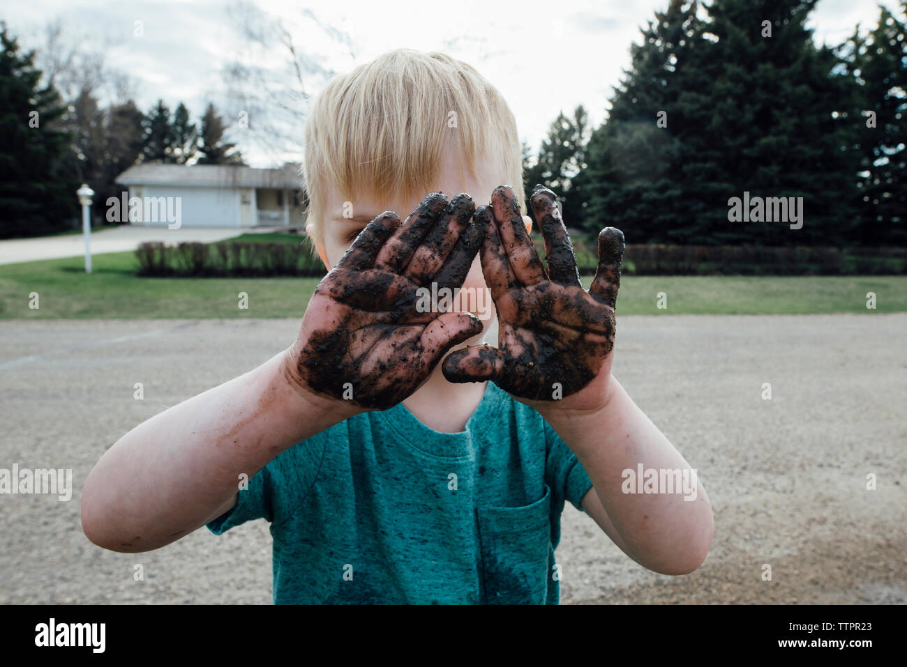 Boy with dirty hands standing on road Stock Photo