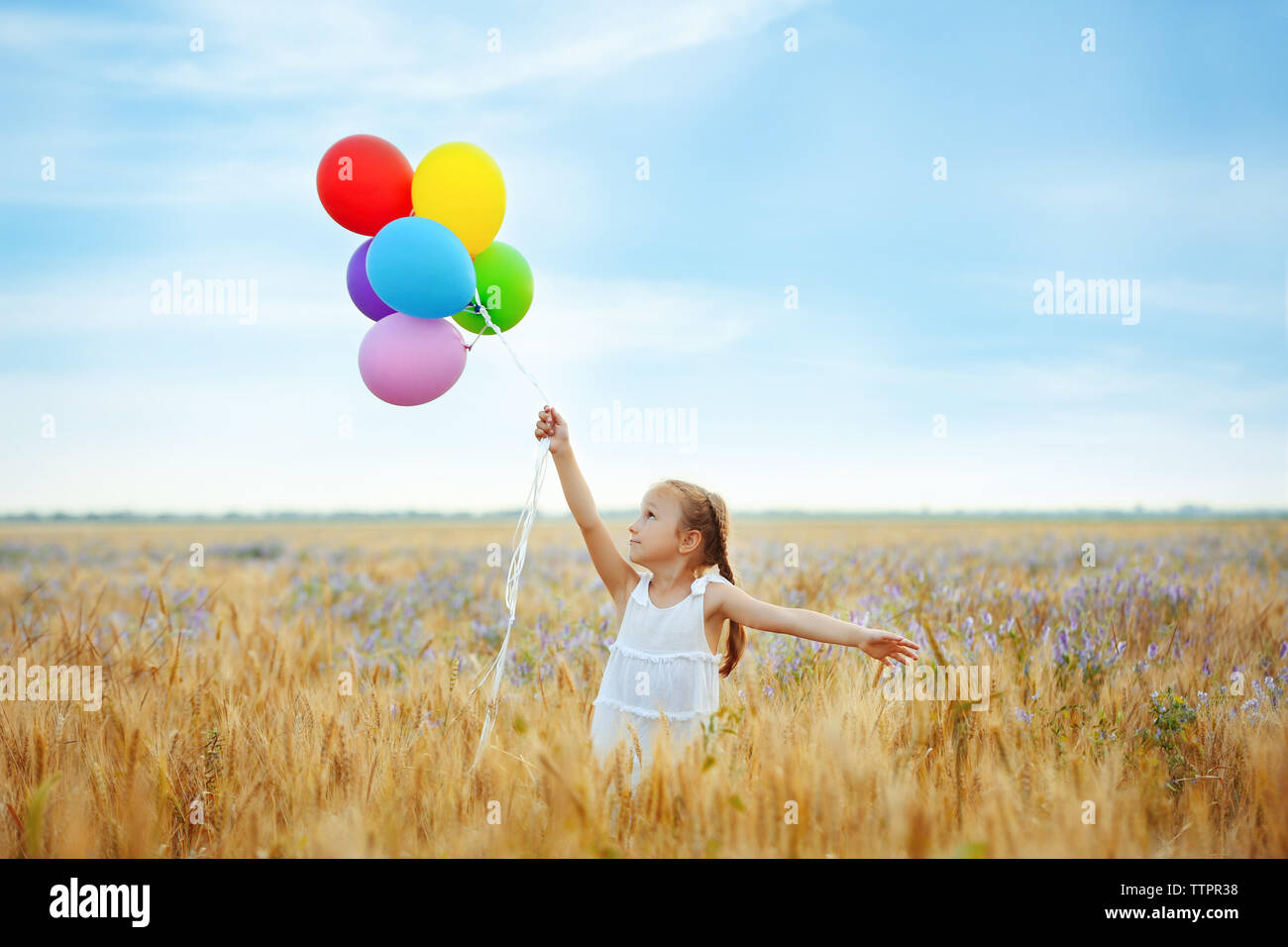 Little happy girl with balloons in the field Stock Photo - Alamy