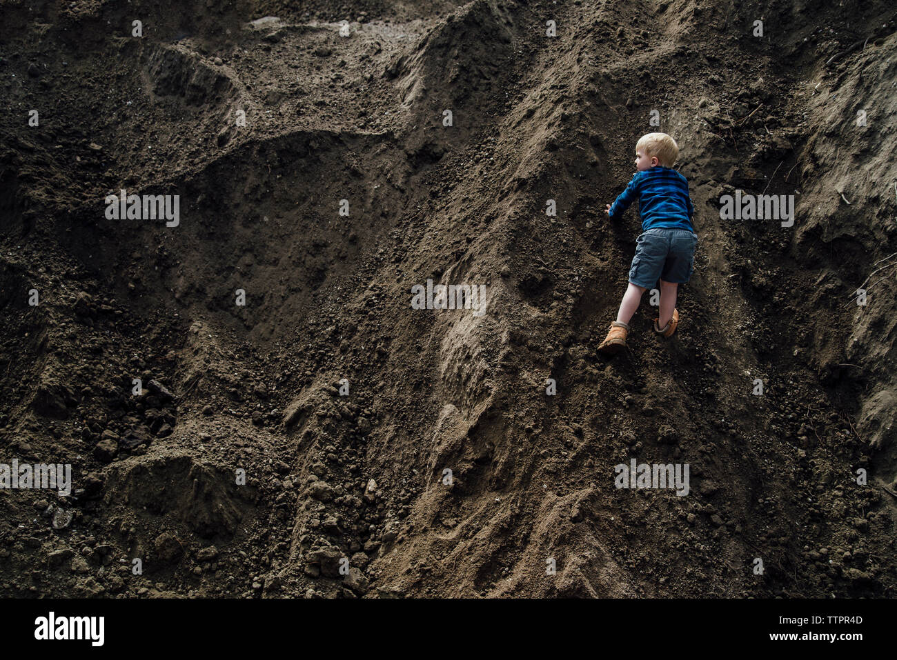 Rear view of boy climbing on hill Stock Photo