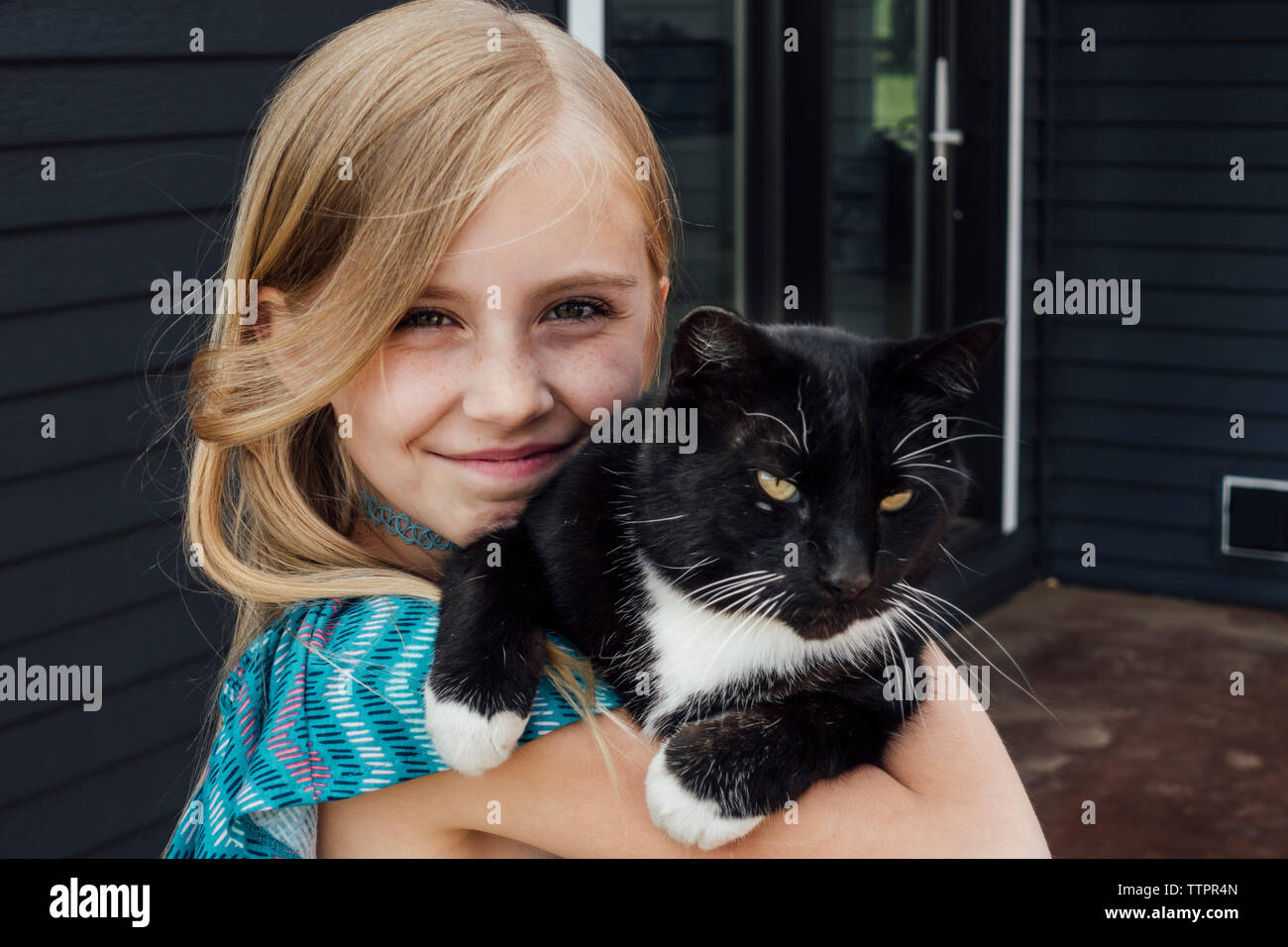 Close-up portrait of girl with cat standing against house Stock Photo