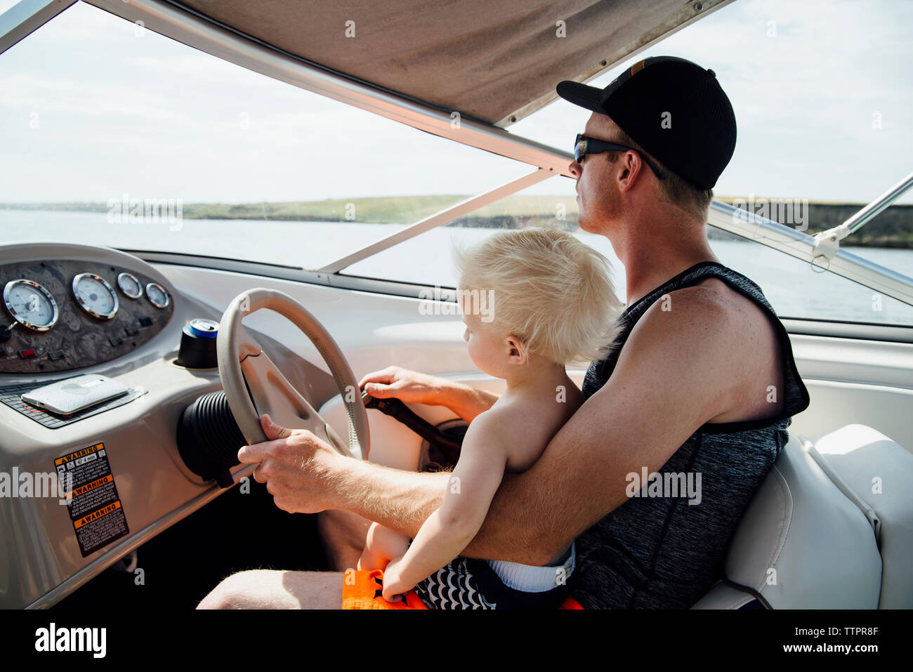 Side view of father with son driving motorboat Stock Photo - Alamy
