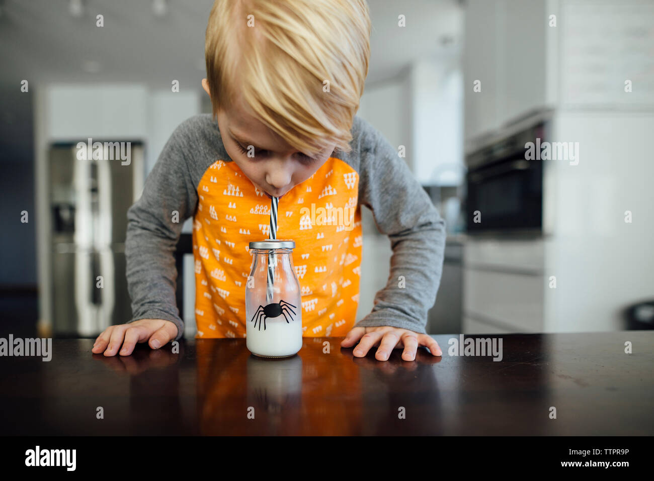 Boy drinking milk at table Stock Photo