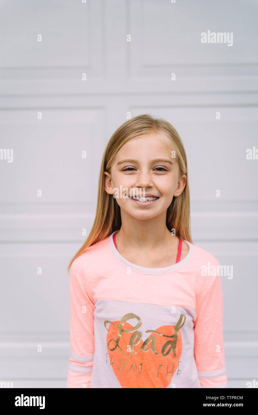 Portrait of smiling girl standing against door Stock Photo - Alamy