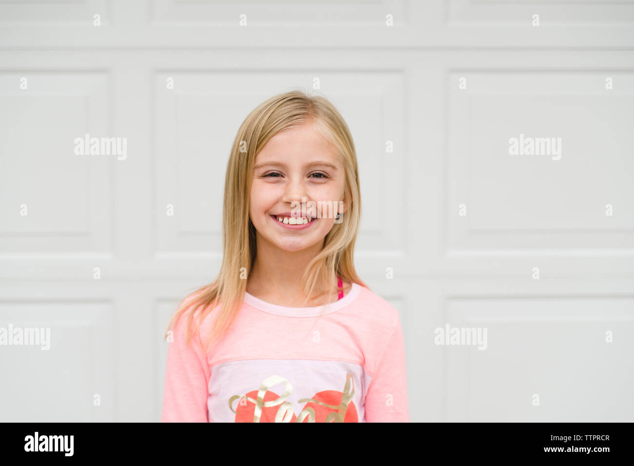 Portrait of smiling girl standing against door Stock Photo - Alamy