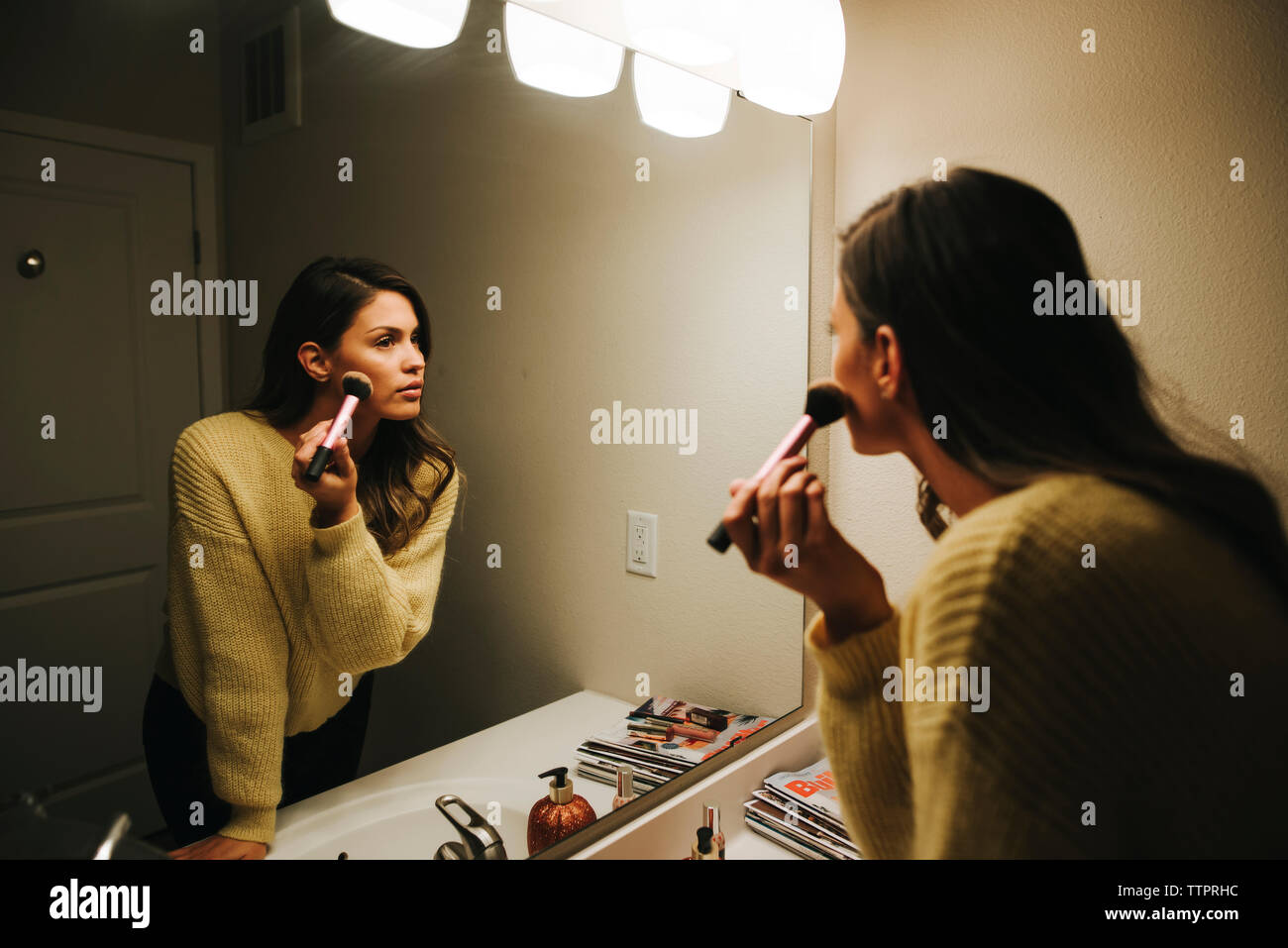 Woman applying make-up reflecting on mirror Stock Photo