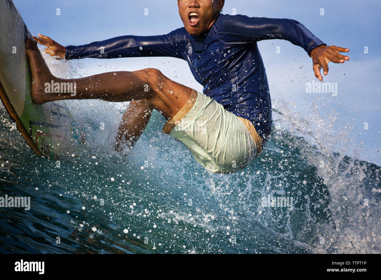 Excited young man surfing on sea Stock Photo