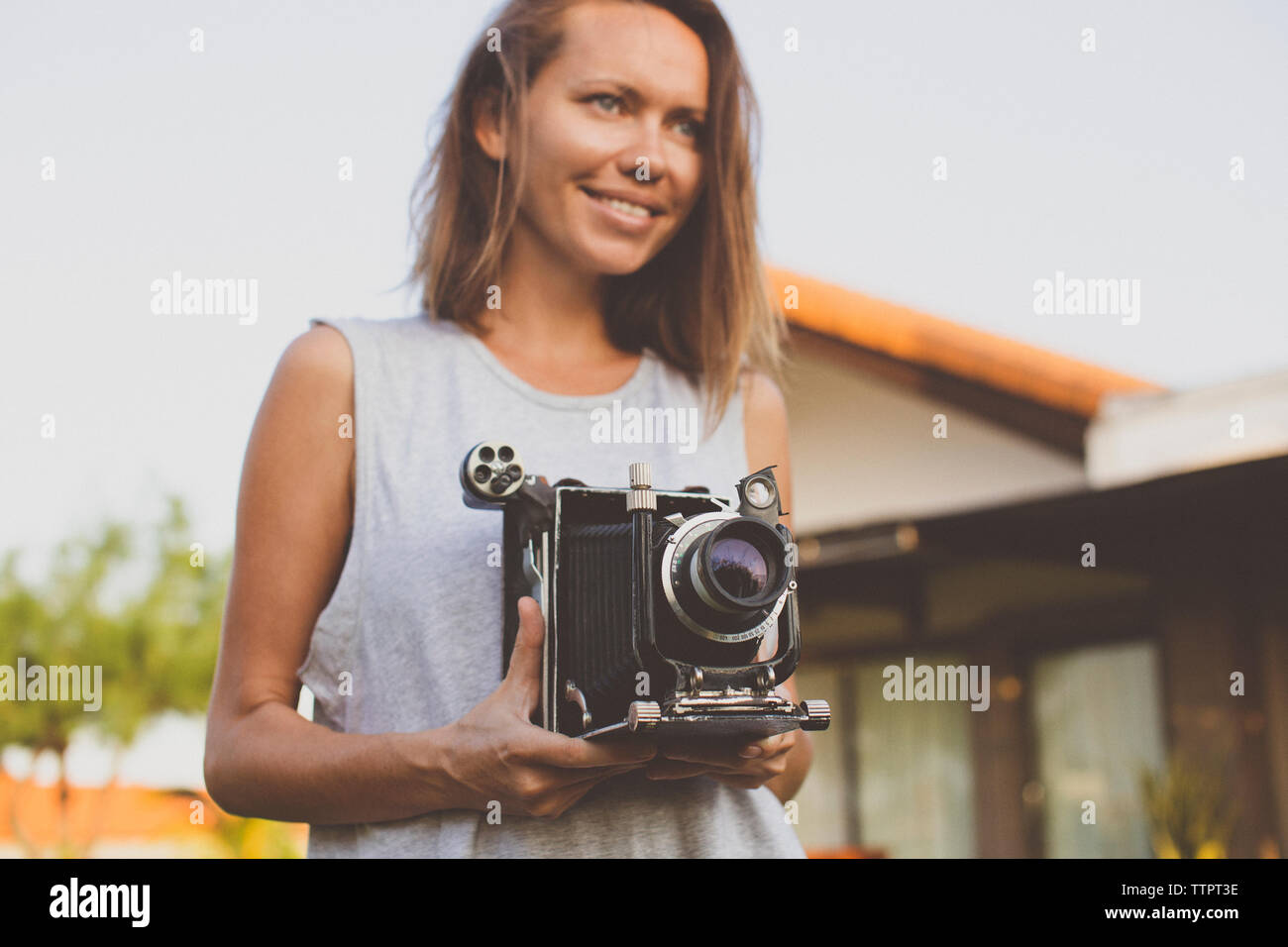 Mid adult woman holding old-fashioned video camera at yard Stock Photo