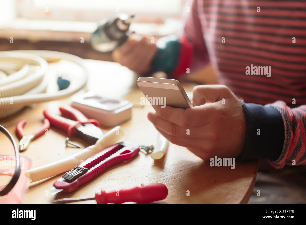 Midsection of man using smart phone at workshop Stock Photo