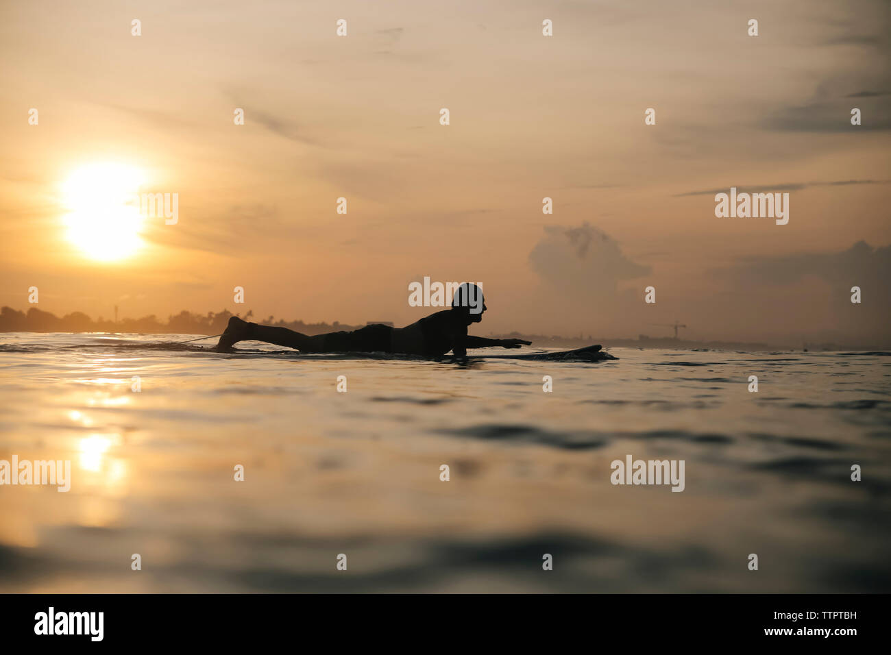 Side view of silhouette man surfing on sea against sky during sunset Stock Photo