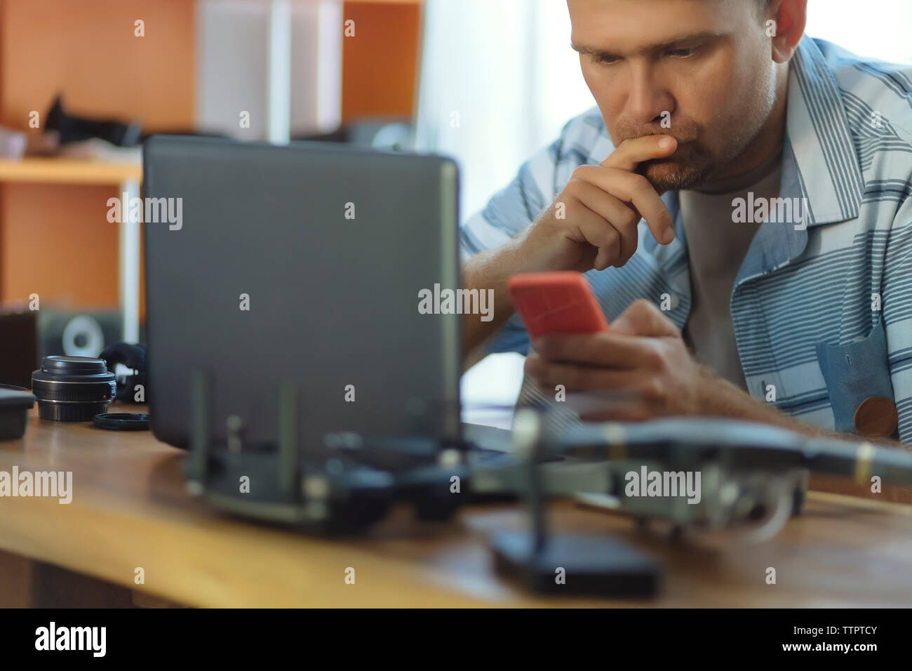 Engineer using mobile phone while sitting at table in office Stock Photo