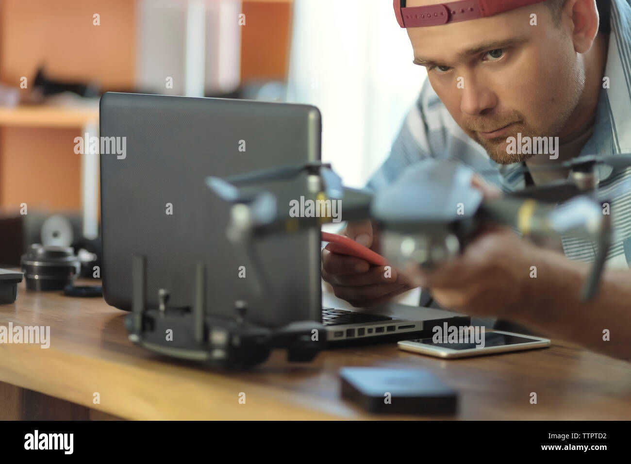 Engineer using mobile phone while examining quadcopter at table in office Stock Photo