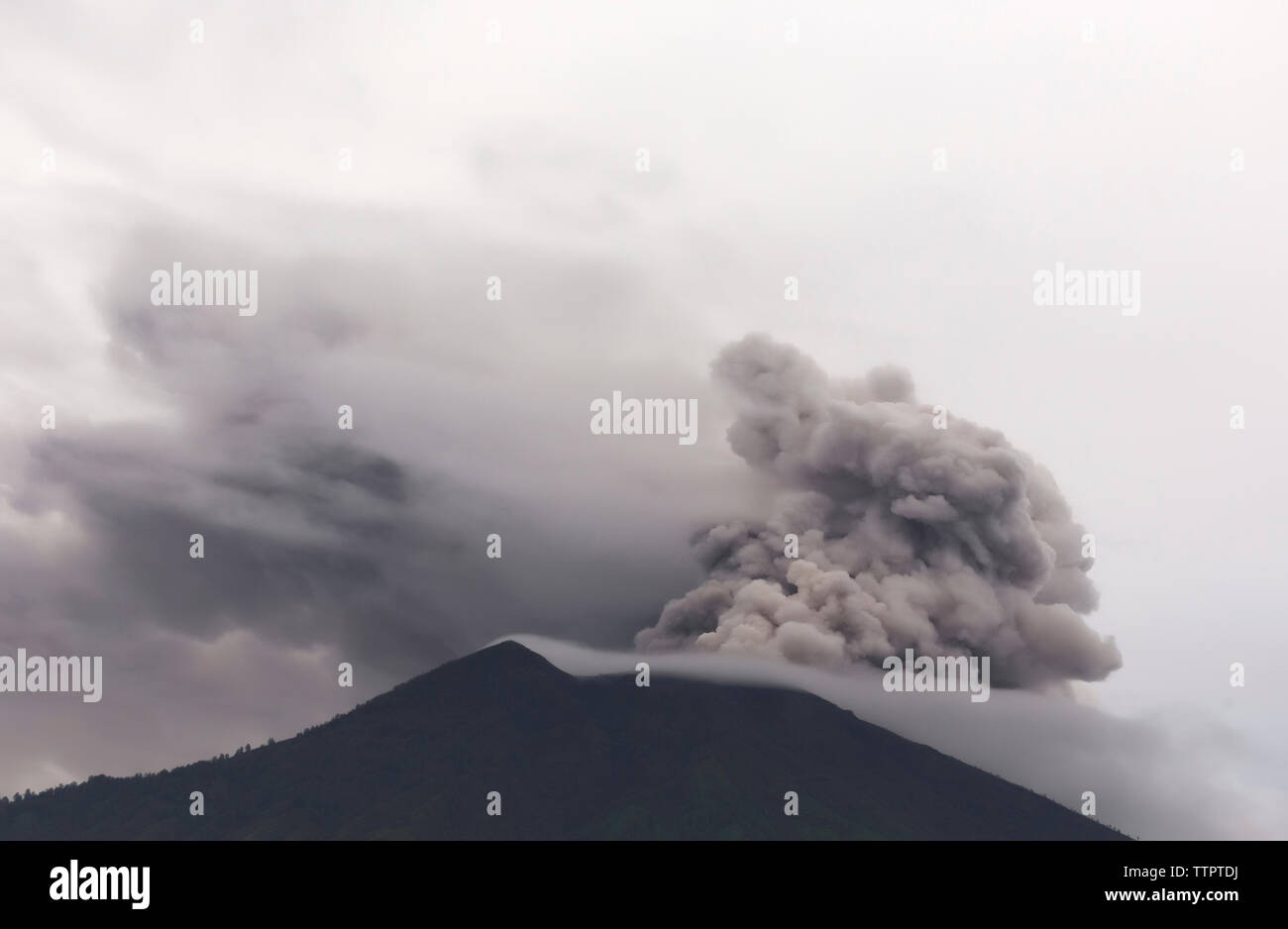 Scenic view of smoke erupting volcanic mountain against sky Stock Photo