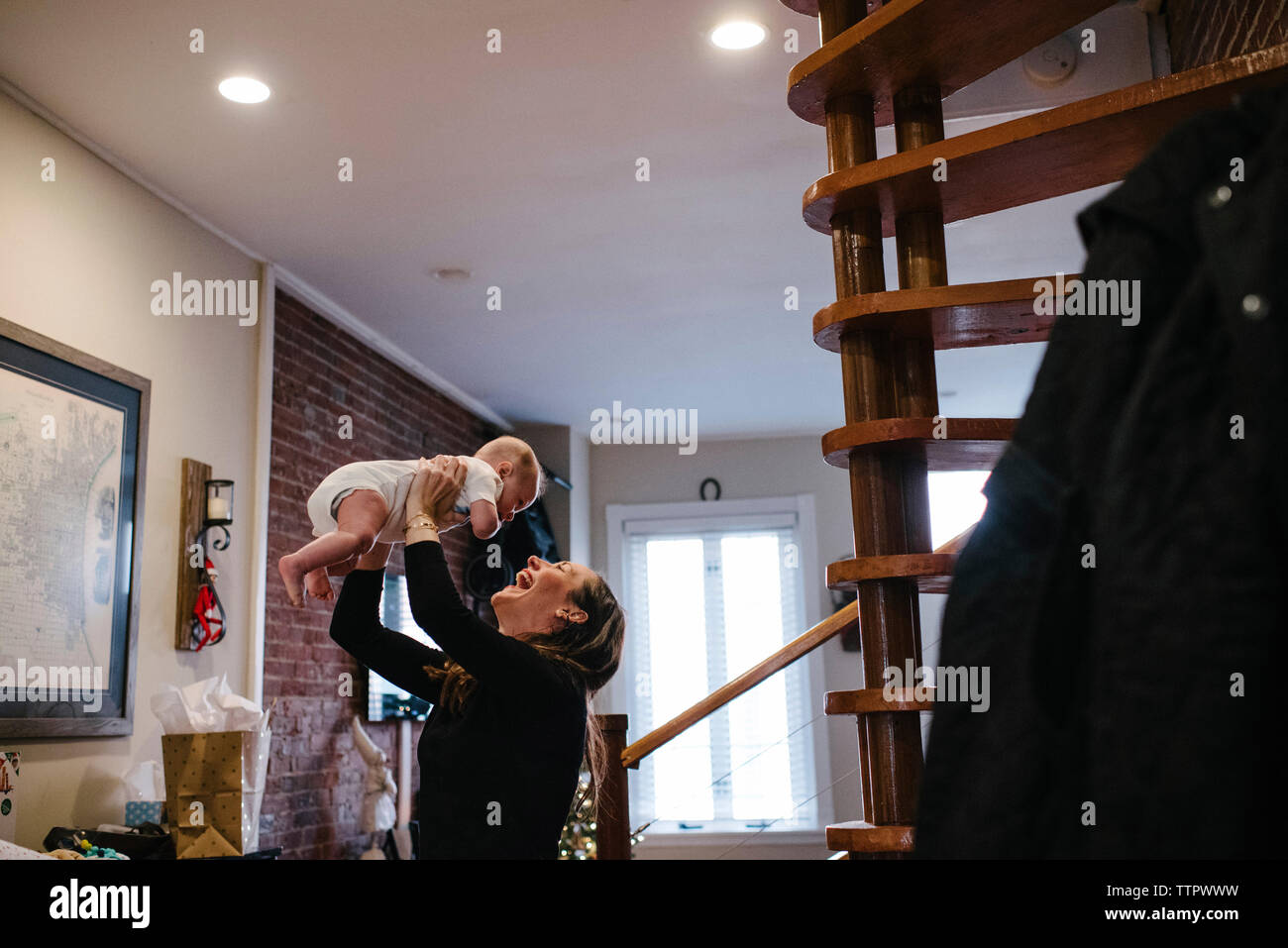 Happy mother picking up daughter while standing at home Stock Photo
