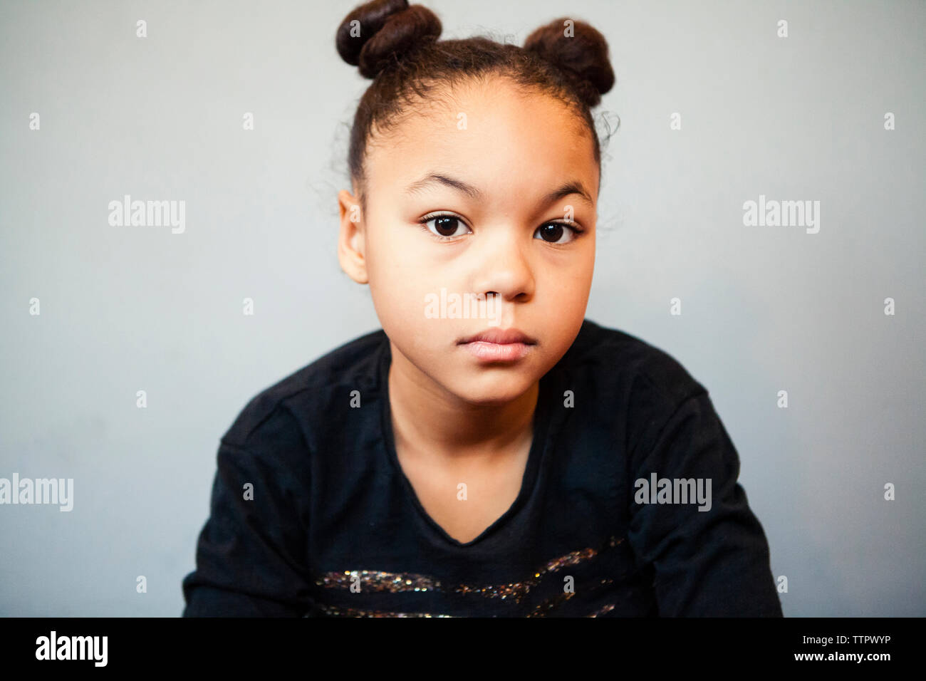 Portrait of confident girl with pigtails against wall at home Stock Photo