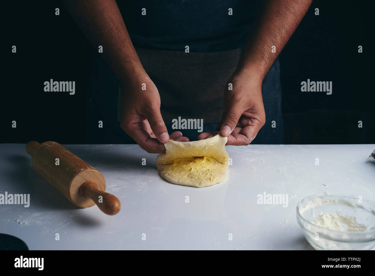 Midsection of man preparing food at table while standing in bakery Stock Photo
